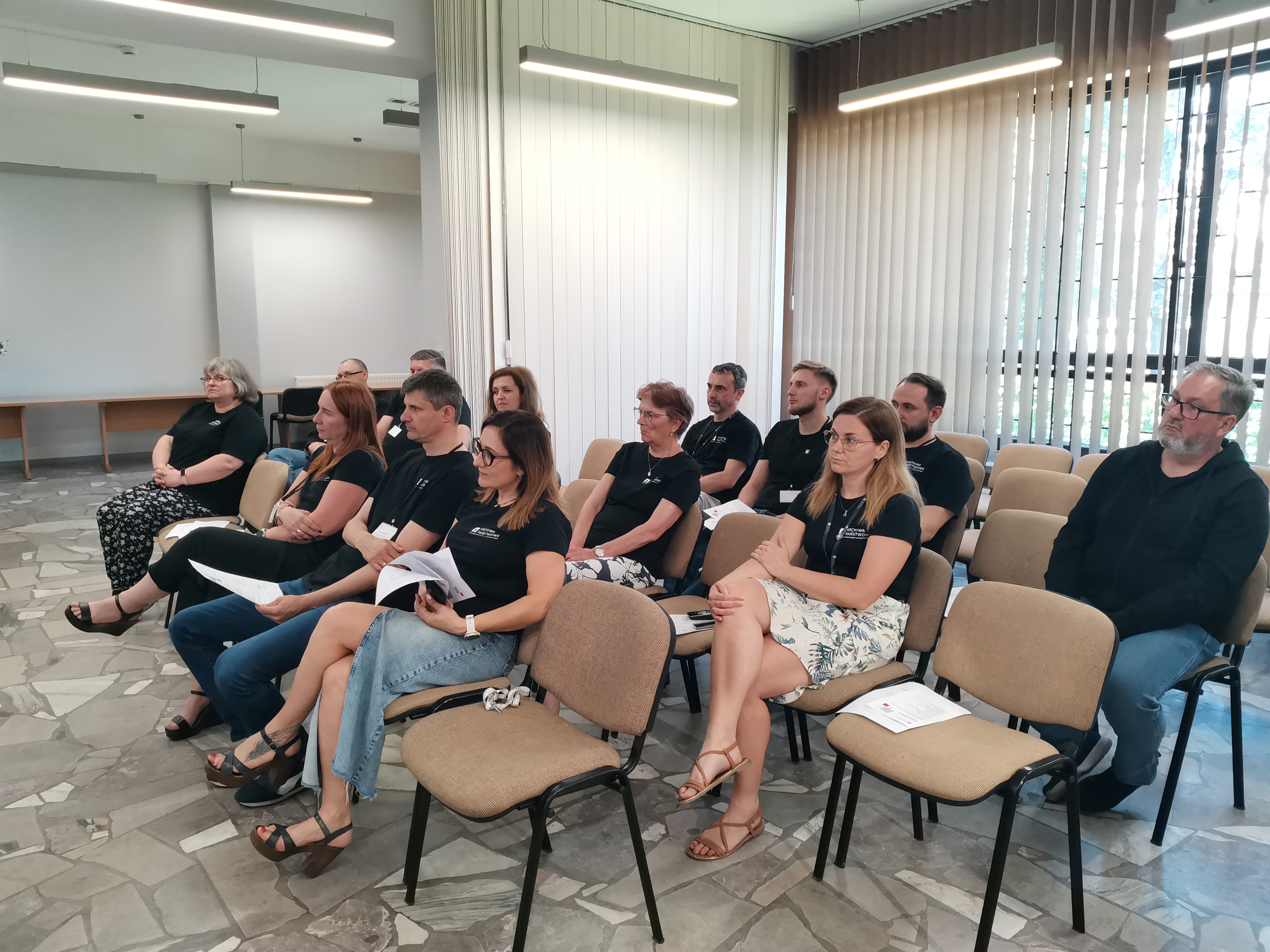 Grupa siedzących kobiet i mężczyzn na sali