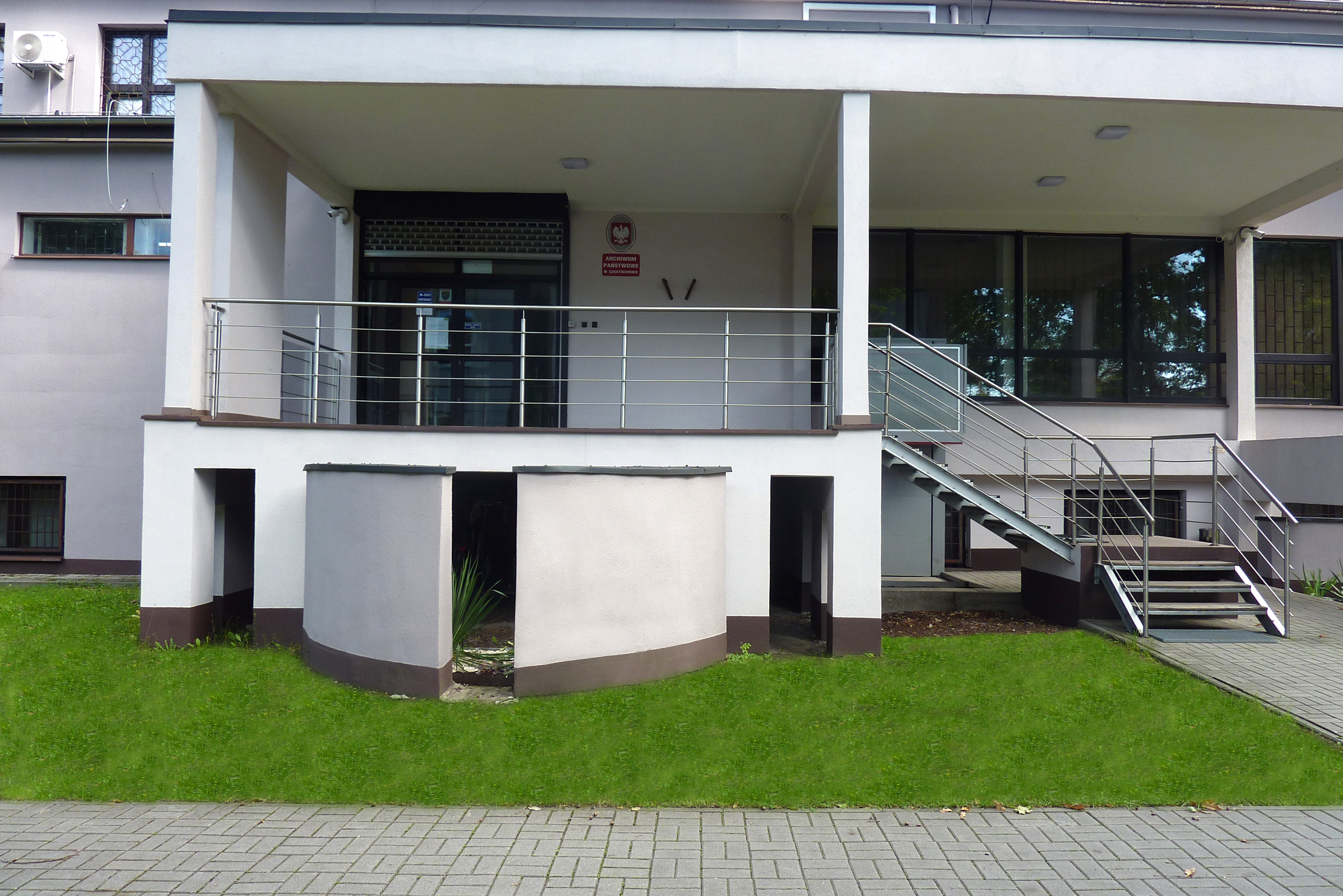 Wejście do budynku z tarasu do którego prowadzą łamane schody z prawej strony.