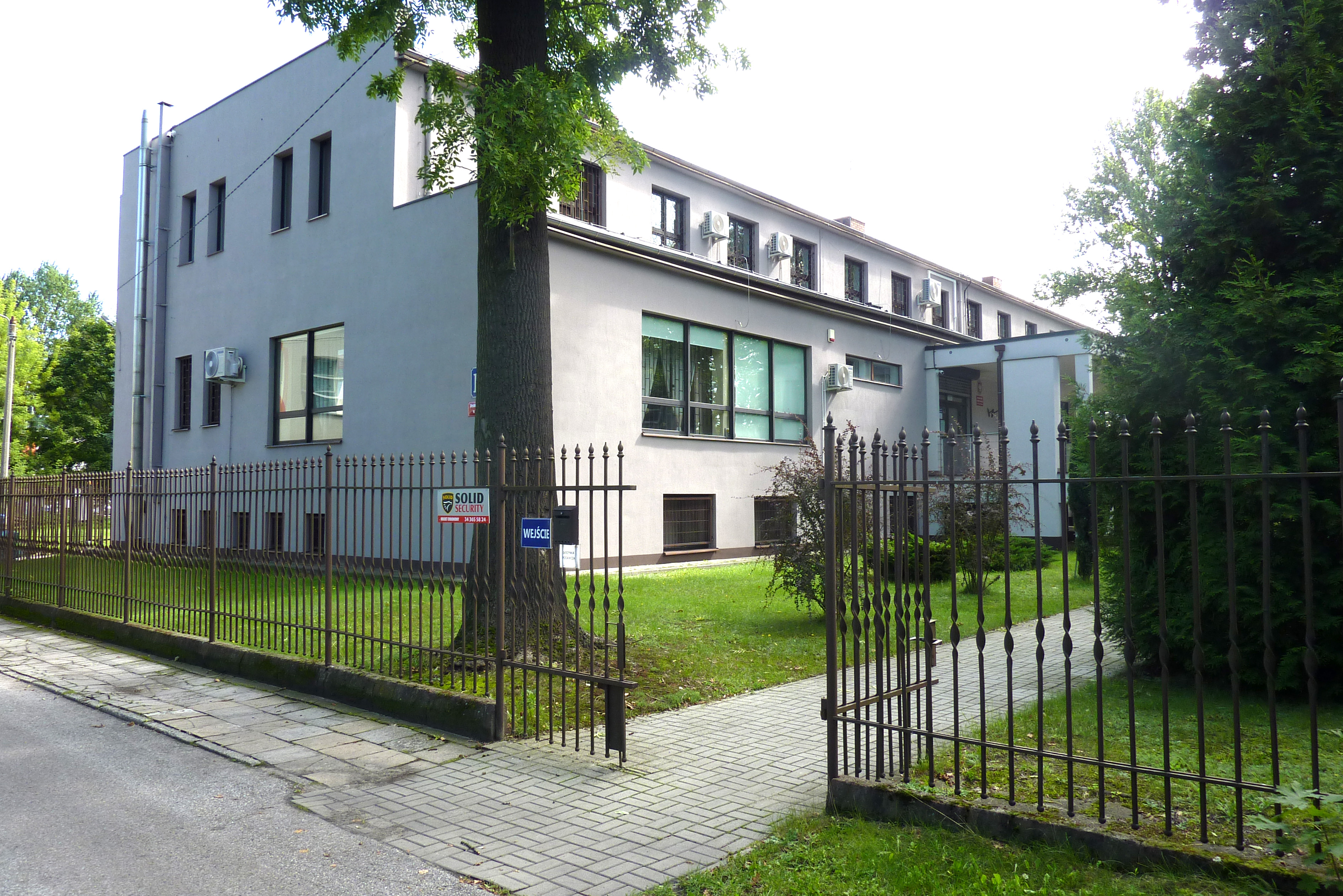Widok otwartej furtki i budynku Archiwum Państwowego w Częstochowie.